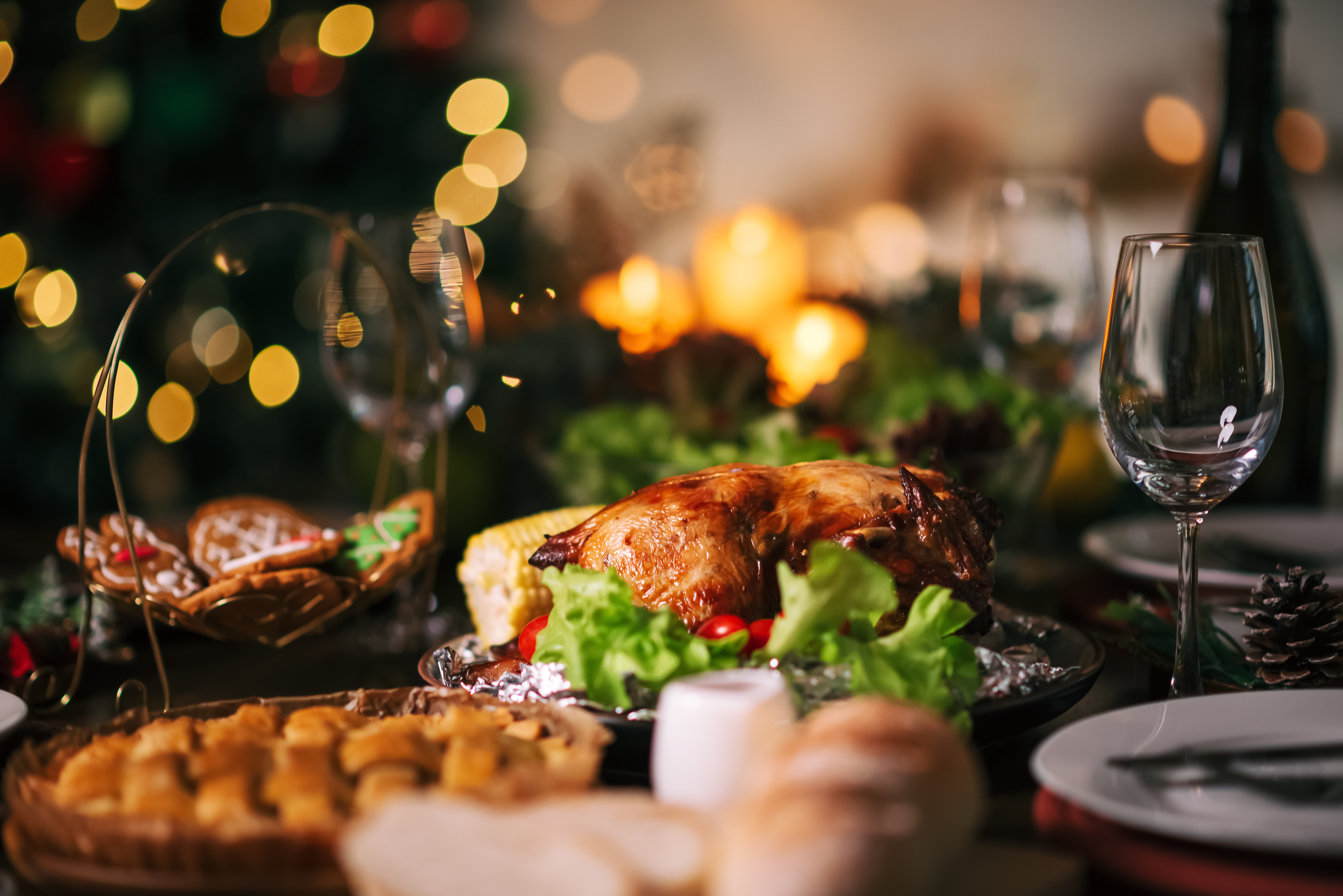 Close up Christmas or Thanksgiving dinner table infront of fireplace and xmas tree decorated at home. Holiday and festival spending time together with family or friends .